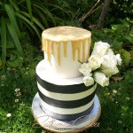 Butter cream cake with golden drip and black and white stripes, fresh flowers