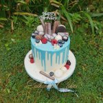 Light blue chocolate drip cake with fresh berries and chocolates