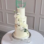 simple 3 tier white butter cream wedding cake with fresh florals across the cake at De Vere Latimer Estate
